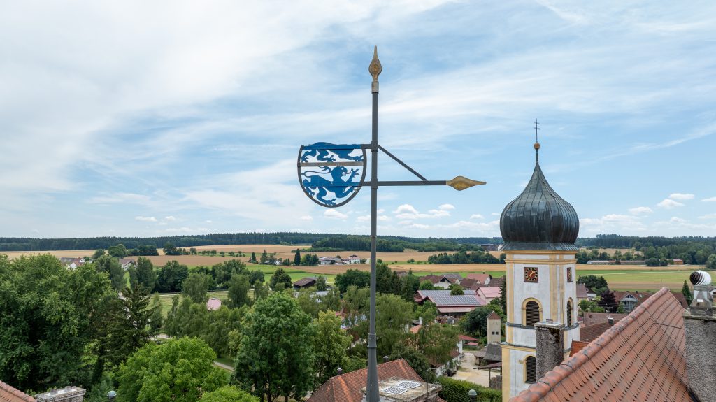 Wetterfahne mit Wappen auf Schloss Wilflingen, im Hintergrund der Kirchturm